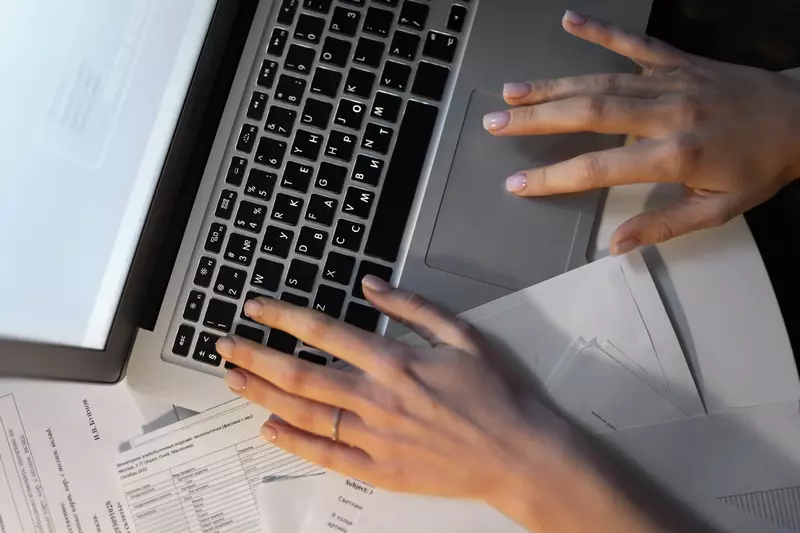 Ręce piszące na klawiaturze laptopa od góry