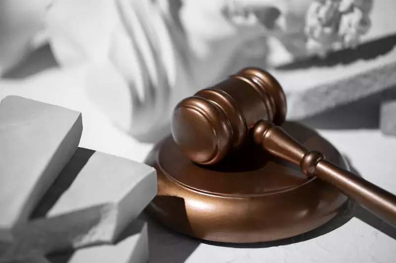 Młotek sędziowski leżący na stole przy białej rzeźbie