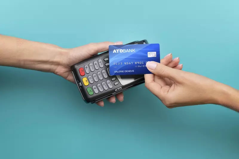 Karta płatnicza zbliżona do terminalu płatniczego na niebieskim tle