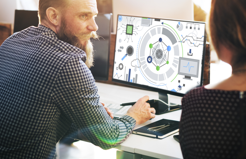 Mężczyzna siedzący przed komputerem z długą brodą i w koszuli w kratkę