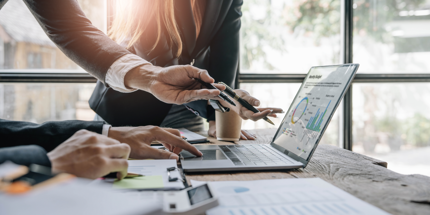 Dłonie trzech osób pokazujące coś na ekranie laptopa